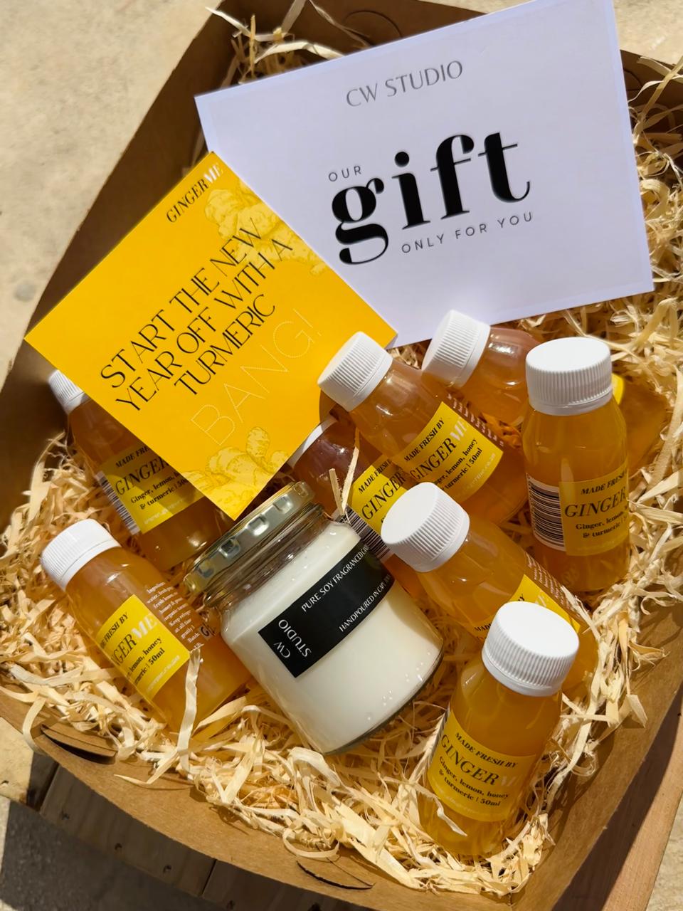 Gift set with bottles labeled 'GingerMe' and a white container, placed in a box with straw-like material.