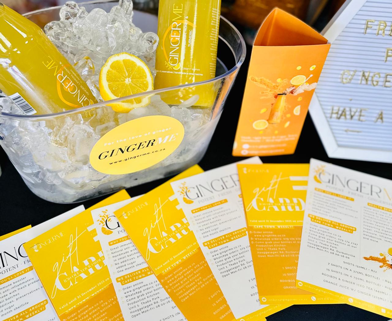 Ginger shot bottles with ice and promotional materials on a table.