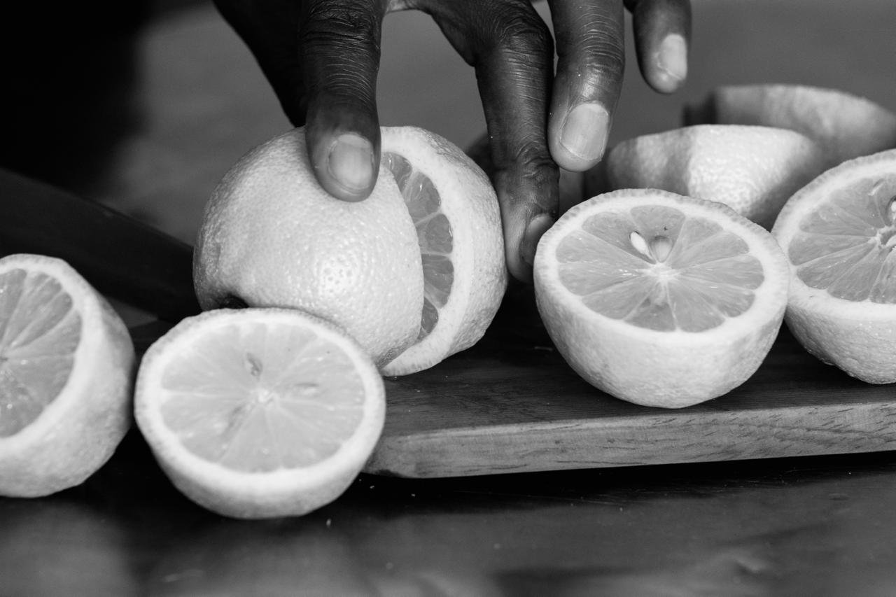 Person holding a lemon with sliced lemons on a wooden board