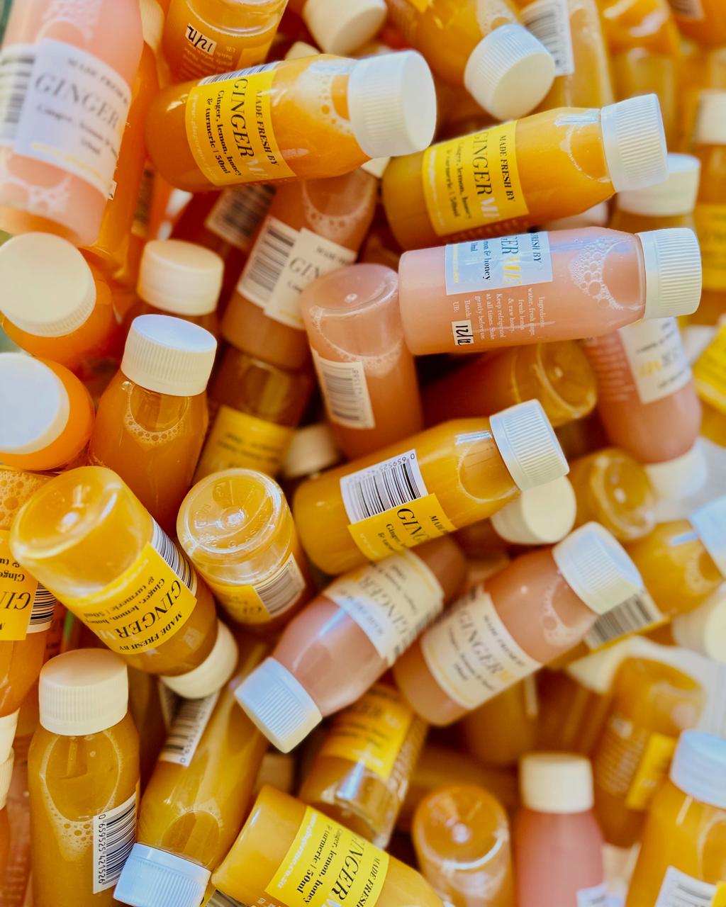 Stack of 50ml 'GingerMe' shot bottles with labels, containing ginger shots in different flavours. 